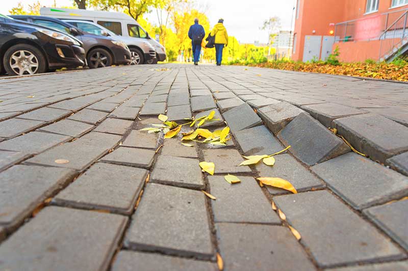 A sidewalk with uneven bricks