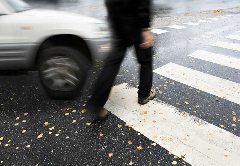 Person on a crosswalk about to be hit by a car